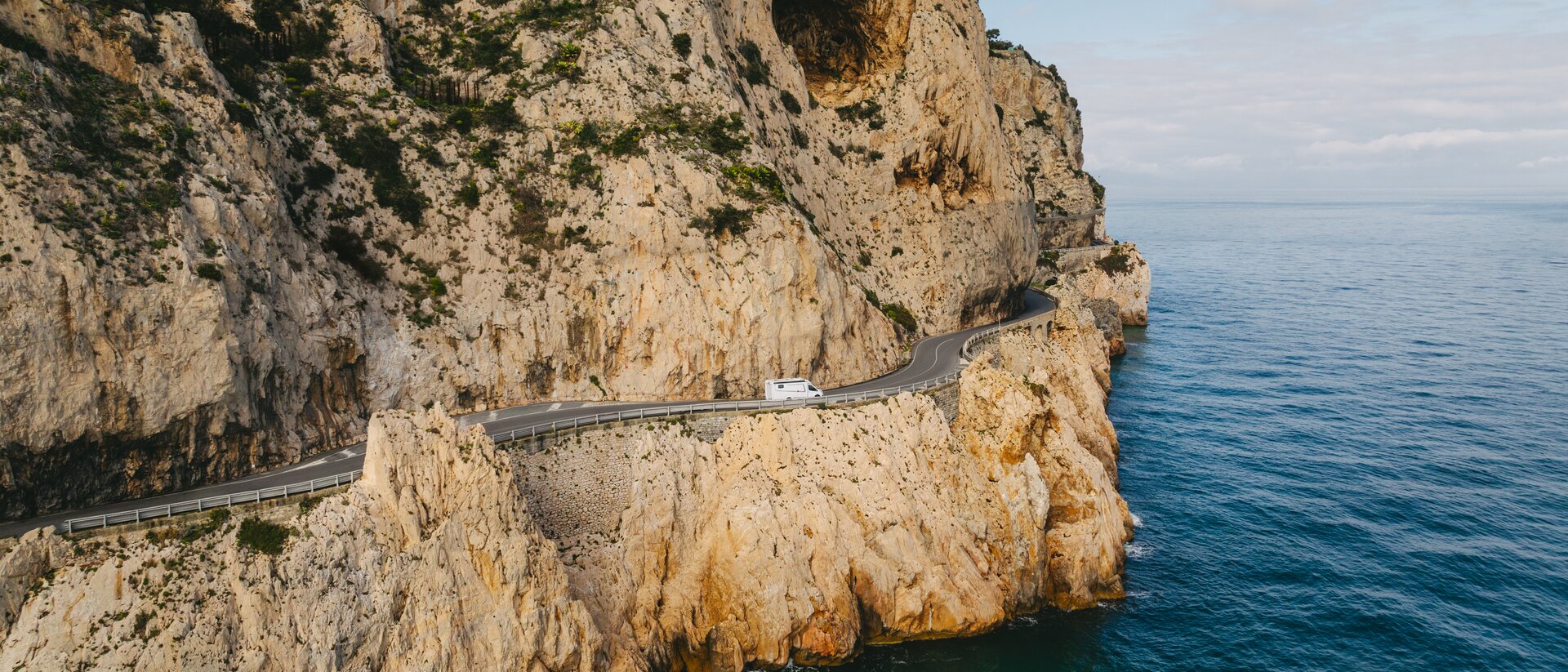 The Etrusco motorhome on a narrow coastal road along steep cliffs, with a view of the sea – pure adventure while camping.