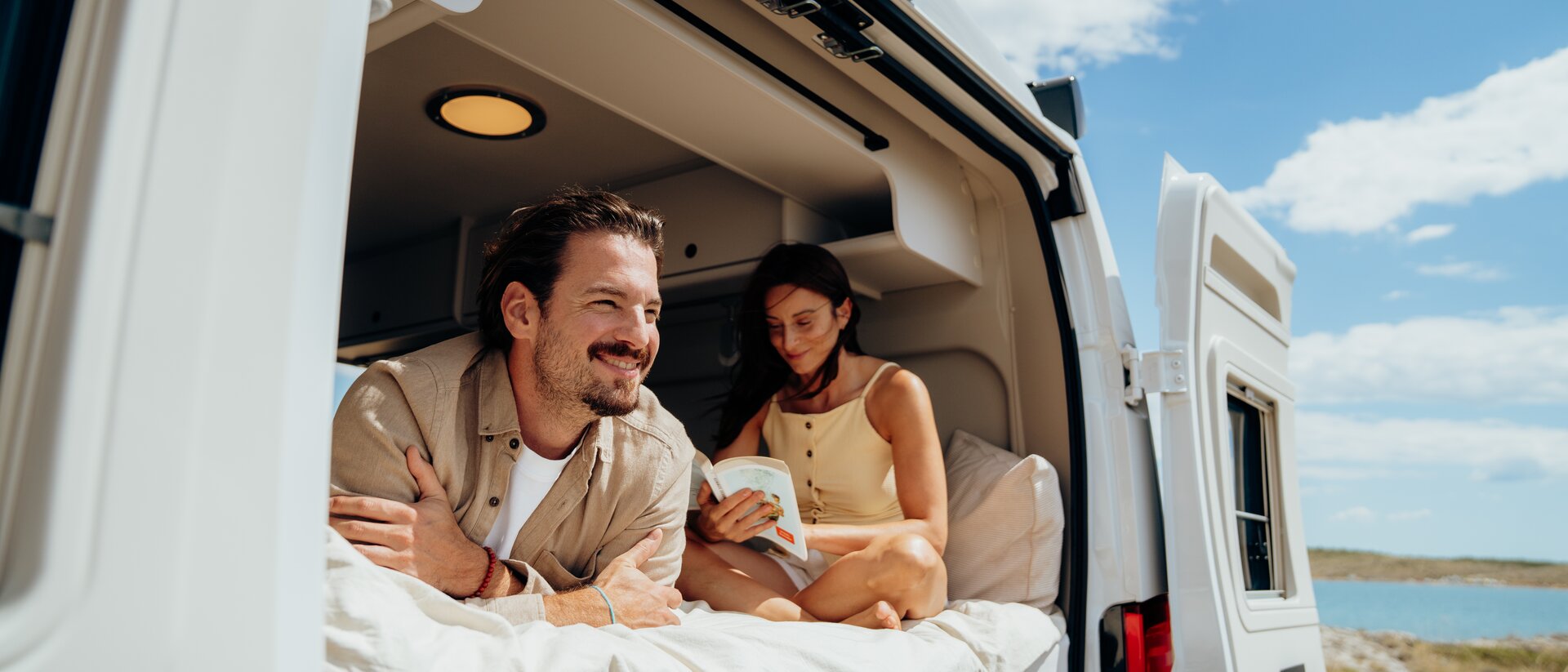 Woman enjoys her coffee in front of an Etrusco semi-integrated motorhome, parked in an idyllic courtyard with Mediterranean charm.