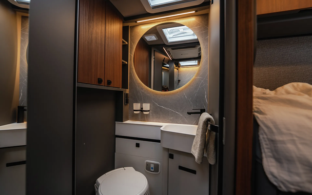 View through the rear garage of the HYMER B-ML T motorhome, loaded with silver suitcases, in front of the port facility with the red freighter