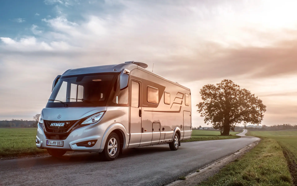 HYMER B-Class Masterline on the road in a flat landscape with green meadows and trees