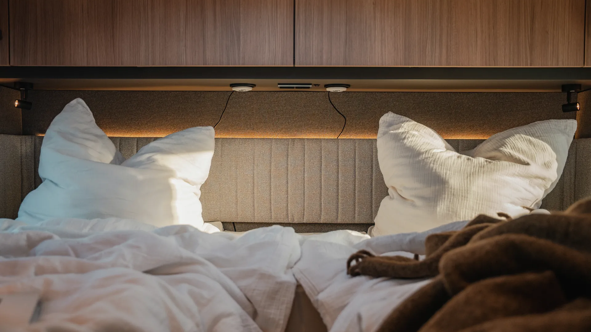 Overhead lockers in premium ribbed HPL finish define the clear material language and give the sleeping area additional depth and quality.