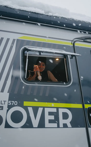 View from the passenger side outside into the kitchen window of the HYMER ML-T 570 CrossOver, a woman is seen in the window