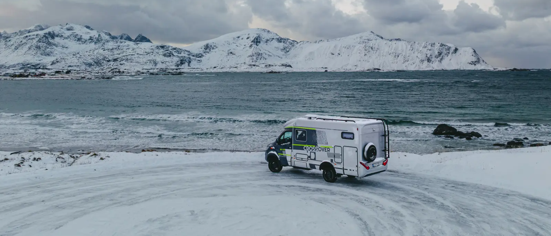 HYMER ML-T 570 CrossOver parked at a viewpoint, the sea and snowy mountains in the background